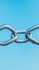 Naklejka premium A close-up view of a metallic chain link against a bright blue background, highlighting the strength and connection of the links.