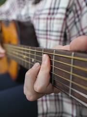 Close-up view of a musician's hands skillfully playing chords on the fretboard of an acoustic guitar, creating music with passion and precision. Vertical photo