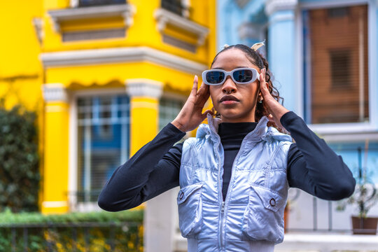 Modern african american young woman placing sunglasses standing outdoors