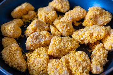 Crispy fried chicken pieces prepared with a crunchy coating in a skillet on a home kitchen stove