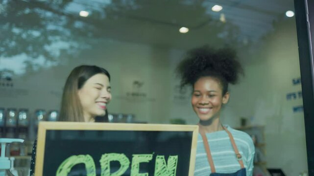 Two woman owner hold open sign at refill shop.