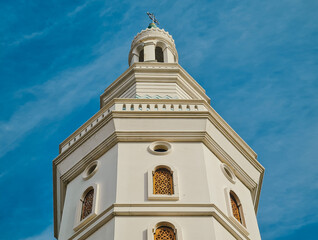 The majestic minaret of Mosque against clear blue sky with some clouds taken from ground. low angle photography.