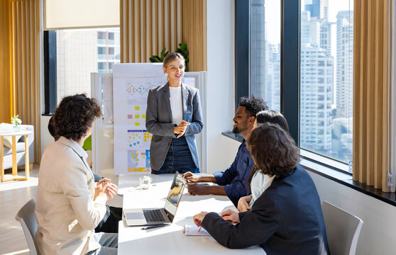 Caucasian woman sale manager is showing annual report chart to her colleagues in the executive meeting for next year plan with market share increase for global business and investment - Powered by Adobe