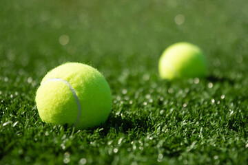 Yellow tennis ball on green sports ground with artificial grass covering. Close up. Copy space. Healthy lifestyle concept.