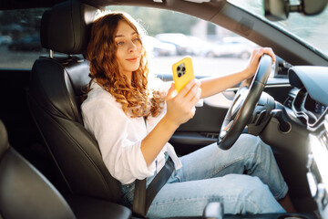 Female driver use smart phone in the car. Navigating. Movement concept, modern technology