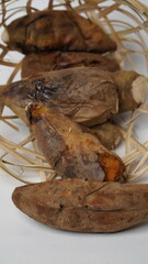 Cilembu roasted sweet potatoes in a bamboo basket are placed on a white base and background (isolated white).
