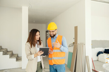 Smiling architect and interior designer collaborating on a project while standing in house in...