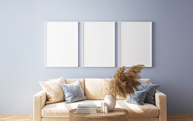 Mockup of three empty white picture or photo frames on blue walls. Plush beige furniture, pampas grass and a stylish coffee table with books and accessories create a cozy, inviting atmosphere.