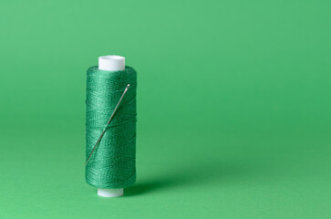 Green thread spool with needle close-up background with copy space for text