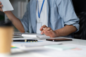 Finance professional calculating budget and managing documents at a desk.