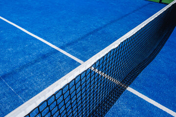 view from the top of the net on a blue padel tennis court, racket sports concept background