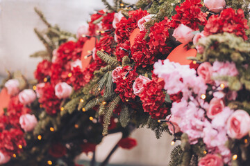 A colorful arrangement of red and pink flowers, surrounded by greenery, brings life to an outdoor event. Twinkling lights add a magical touch, inviting attendees to celebrate spring’s arrival
