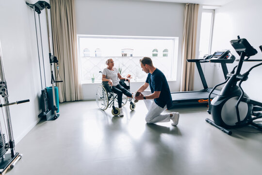 Physiotherapist assisting elderly woman in wheelchair during rehabilitation session