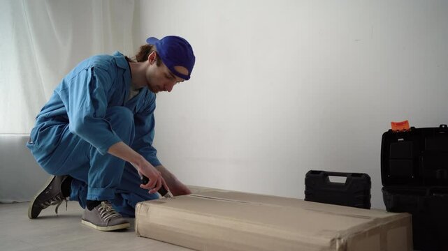 Furniture assembly worker unpacking bookshelf. Young handyman doing assembly move into new house.
