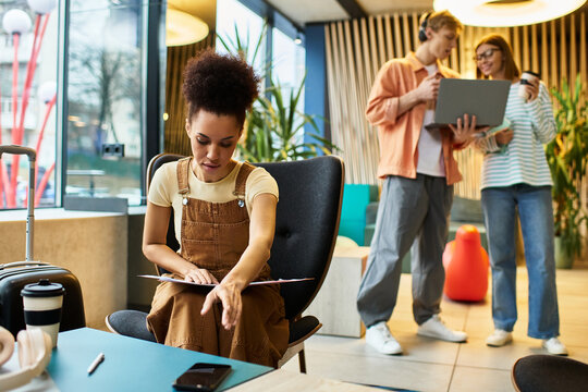 Colleagues collaborating in hotel lobby during business trip while being productive