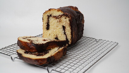 Brownie babka bread that has been partially cut is served using a cooling rack with a white background (isolated white).