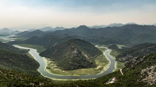 Time lapse drone shot of Pavlova strana River Loop with fast moving boats on the crnojevica River in Lake skadar Montenegro with mountains in the background