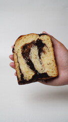 Hand holding a slice of babka brownie bread on a white background (isolated white).