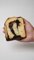 Hand holding a slice of babka brownie bread on a white background (isolated white).