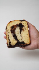 Hand holding a slice of babka brownie bread on a white background (isolated white).