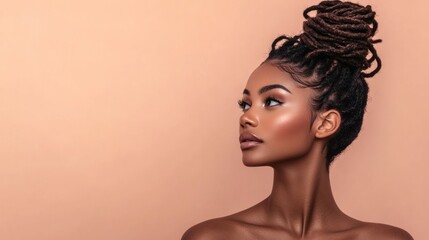 Studio portrait of a Black woman with twisted faux locs styled in a messy bun, wearing natural makeup, standing against a soft peach background, showcasing low-maintenance beauty