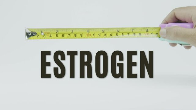 "Estrogen" text with a tape measure on a white background, symbolizing precision in measuring hormonal balance, health, and biological regulation
