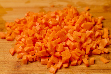 carrot cut into cubes on a wooden chopping board