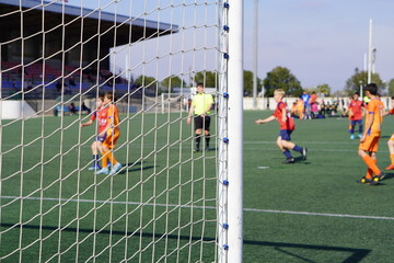 diverse team of pre-teen soccer players out of focus with goal in the foreground