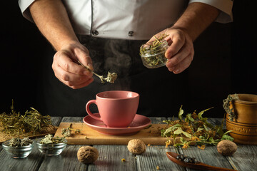 Hands skillfully add aromatic herbs to a warming cup, releasing steam as the comforting atmosphere...