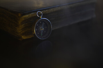 Vintage Compass on Antique Book in Dim Lighting - Navigational and Historical Concept