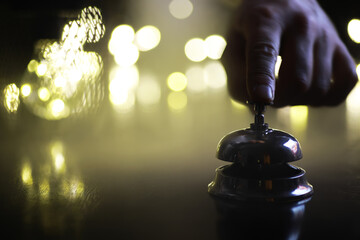 Hand Pressing Service Bell in a Dimly Lit Setting with Bokeh Lights in Background