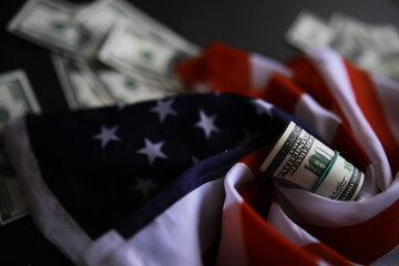 American Flag with Rolled US Dollar Bills and Scattered Cash Symbolizing Economic Power and...