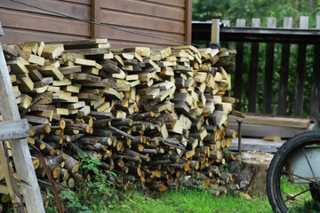 Stack of Firewood Against Wooden Shed Outdoors in Summer