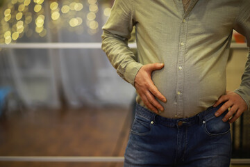Man Holding Stomach Relieving Discomfort in Festive Indoor Setting With Warm Lights