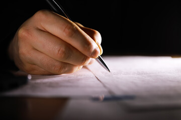 Close-up Hand Writing with Pen on Paper in Dark Lighting