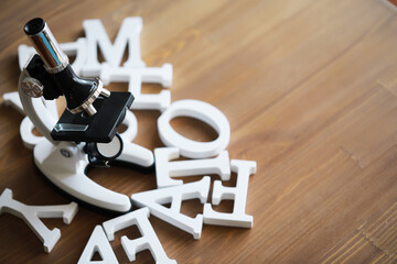 Microscope Amid Scattered Alphabet Letters on Wooden Table - Education and Science Conceptual Image
