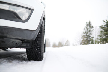 Close-up of a Car Tire Driving on Snowy Road in Winter Landscape