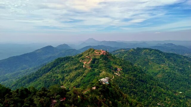 Drone aerial landscape of Ambuluwawa Tower in valley village forest region with trees on hills mountain peak hiking trails Gampola town Kandy District Sri Lanka Asia travel tourism holidays