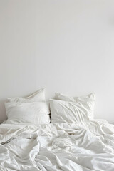 Cozy white bedding with rumpled sheets and pillows in a minimalist bedroom setting