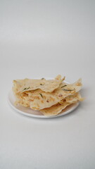 A portion of rempeyek with shrimp topping served on a white plate and placed on a white place and background (isolated white).