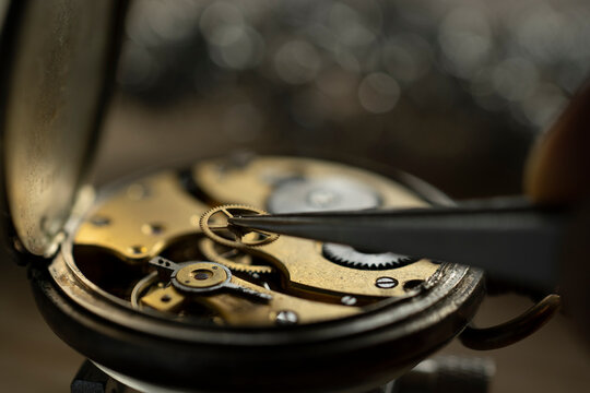Professional watchmaker repairer working on an old vintage pocket watch in a workshop.
