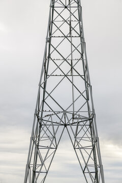 Starlings resting in a high voltage power pylon against with a clouded sky in the background.