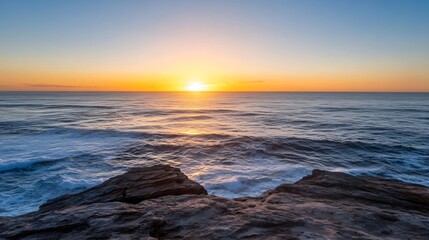Obraz premium Breathtaking view of the sun setting over a tranquil ocean with gentle waves crashing on rocky shore : Generative AI