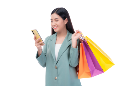 Beautiful Asian woman in a green blazer holding colorful shopping bags and using a smartphone, smiling with excitement while shopping online, isolated on a transparent background