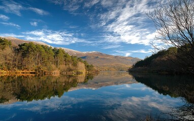 Obraz premium A pristine mountain lake reflecting the blue sky, surrounded by trees