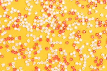 Texture made from acrylic beads scattered on a yellow background.