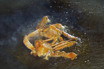 Pieces of hilsa fish are being fried, fried eggplant on a big pan, Fresh crab are being fried