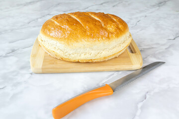 Freshly baked bread on a cutting board and a knife.