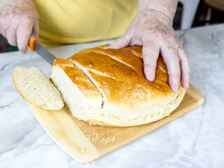 A woman cuts bread into slices. Homemade baking.
