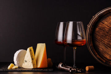 A refined selection of aged cheeses presented on a board, accompanied by a glasses of wine